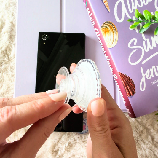 Person holding a white suction cup with a phone and magazine in the background