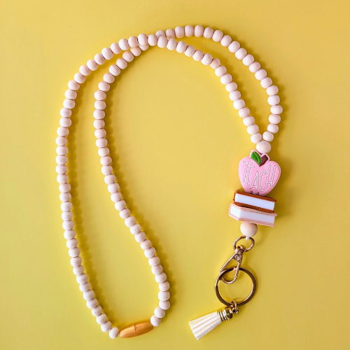 Beaded lanyard with a pink apple-shaped charm on a yellow background