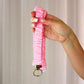 Hand holding a pink textured keychain against a neutral background