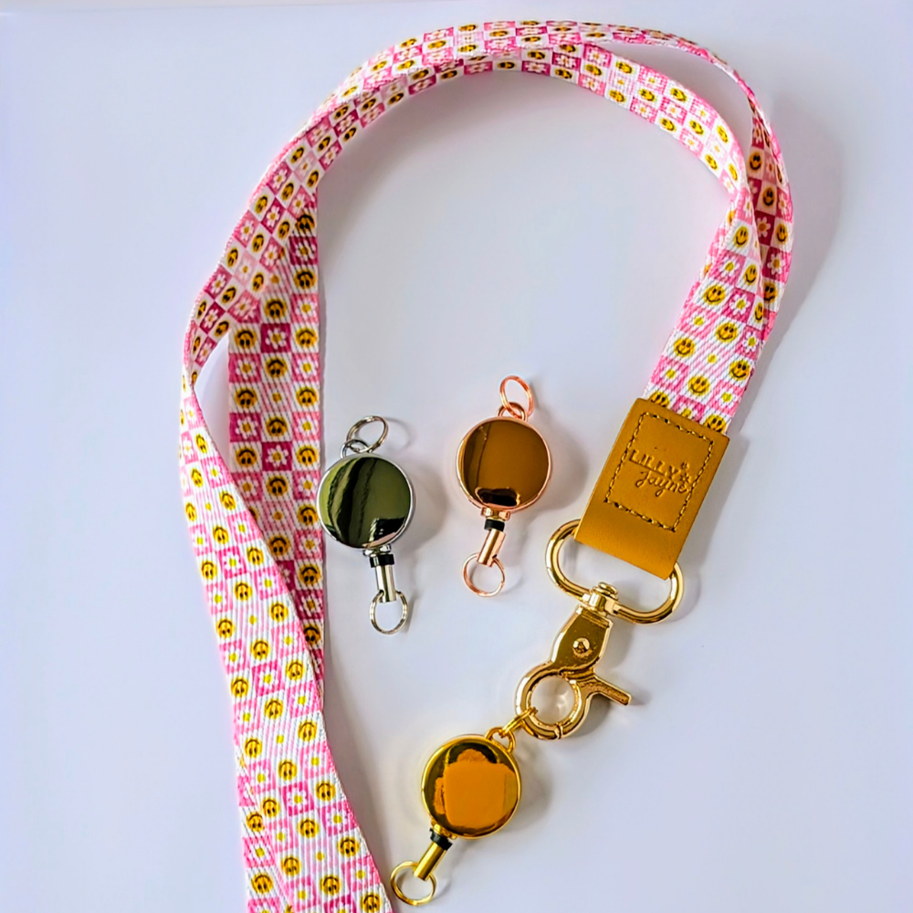 Pink lanyard with gold badge holders on a white background