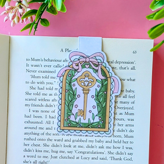 Decorative key and bow bookmark on a book with a pink background