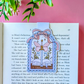 Decorative bookmark with a butterfly design on an open book against a pink background