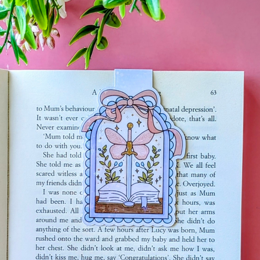 Decorative bookmark with a butterfly design on an open book against a pink background