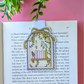 Decorative bookmark with a candle design on an open book against a pink background