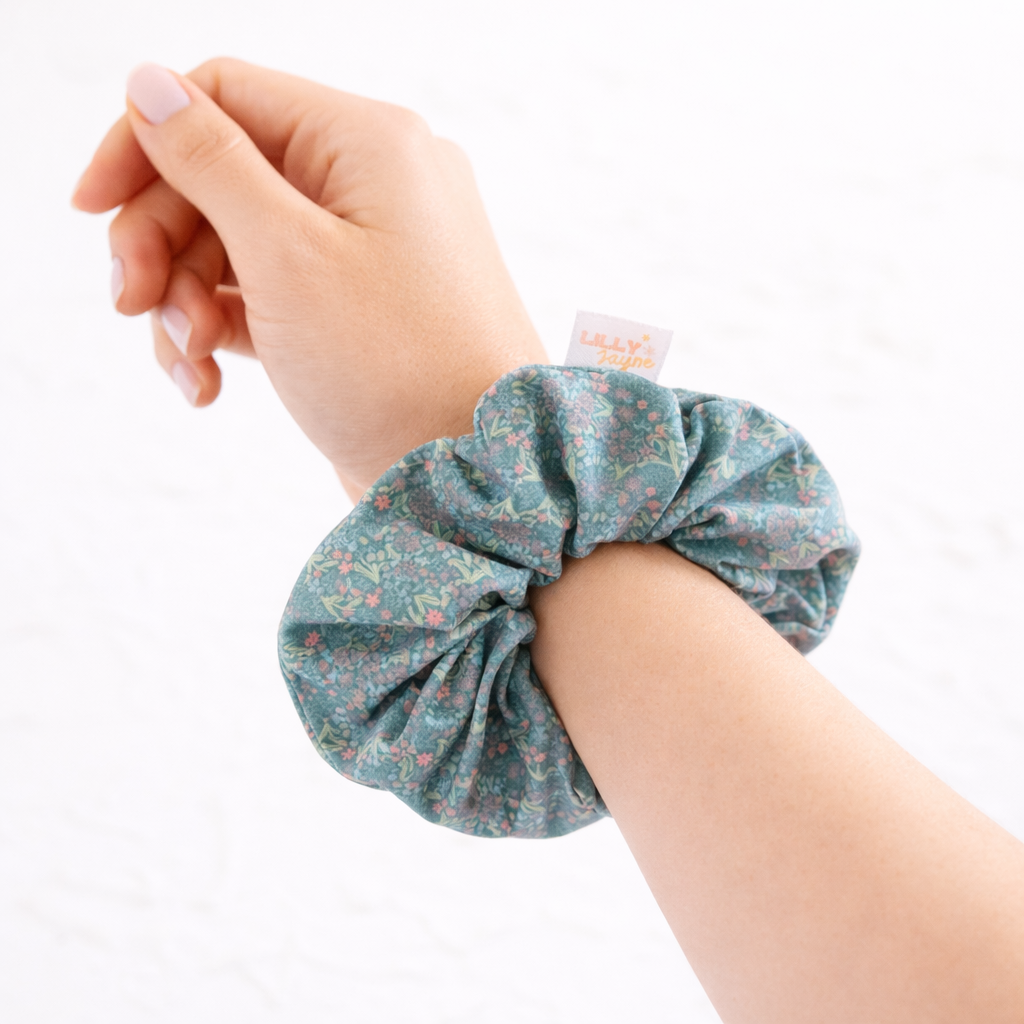 Hand wearing a floral scrunchie on a white background