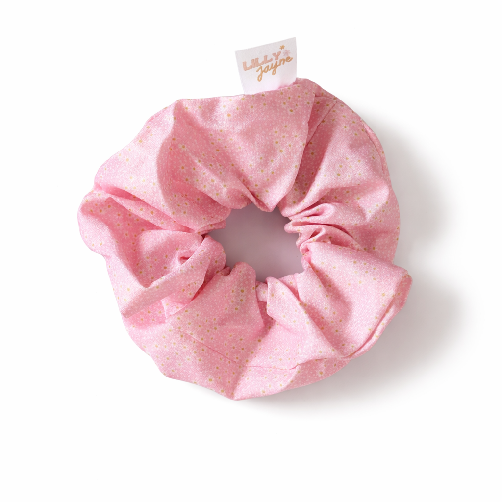 Pink scrunchie with a brand tag on a white background