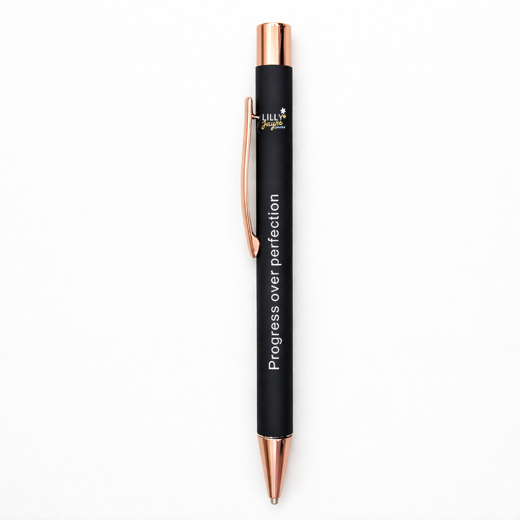 Black pen with rose gold accents and 'Progress over perfection' text on a white background