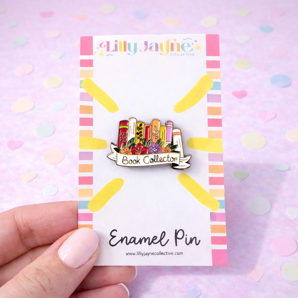 Enamel pin on a colorful card held by a hand with a pastel heart pattern background