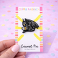 Enamel pin on a colorful card held by a hand with a pastel background