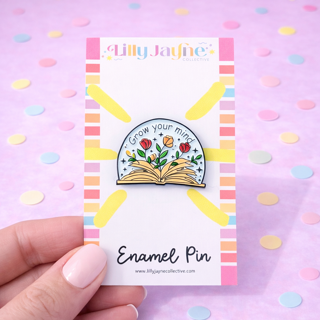 Enamel pin on a colorful card held by a hand with a pastel background