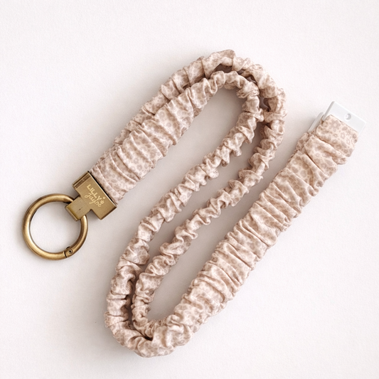 Beige ruched keychain with gold ring on a white background