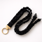 Black scrunchie keychain with gold clasp on a white background