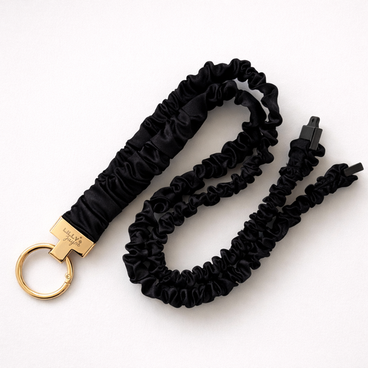 Black scrunchie keychain with gold clasp on a white background