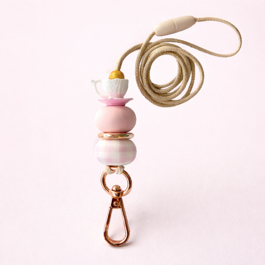 Necklace with pink and white beads and a beige cord on a light pink background