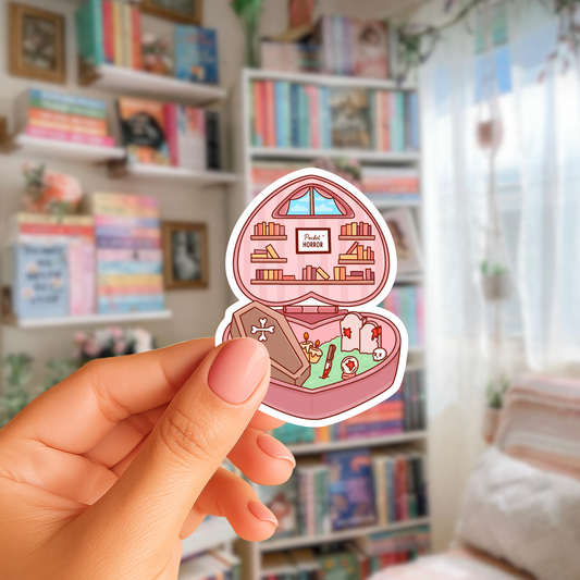 Sticker of a jewelry box with books inside held by a hand in front of a bookshelf.
