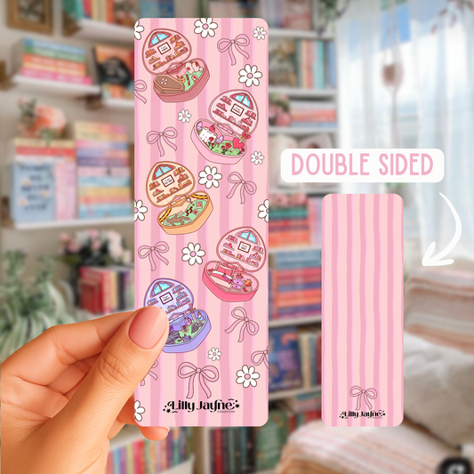 Pink packaging with cartoon designs held by a hand, with a blurred background of books and decor.