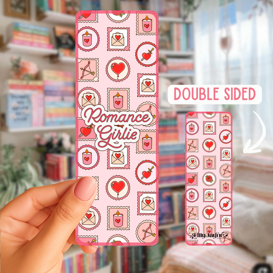 Pink phone case with 'Romance Girlie' design held by a hand, with a blurred background of books and stationery.