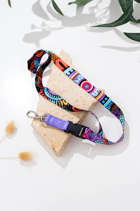 Colorful dog leash on a white surface with green leaves in the background