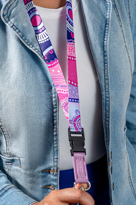 Person wearing a colorful lanyard with a black clip on a denim jacket.