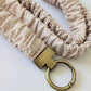 Beige scrunchie with a gold keychain on a white background
