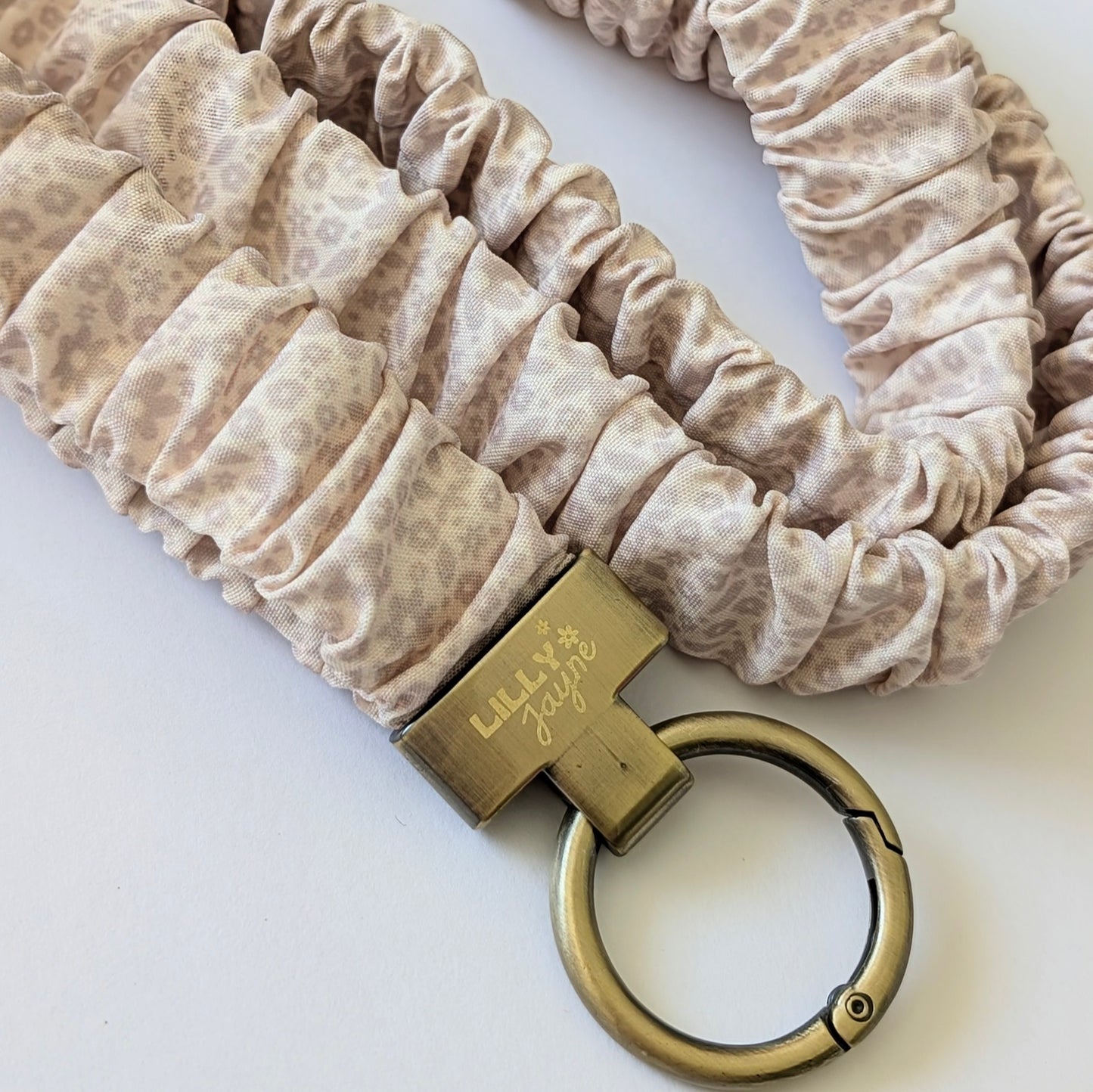 Beige scrunchie with a gold keychain on a white background