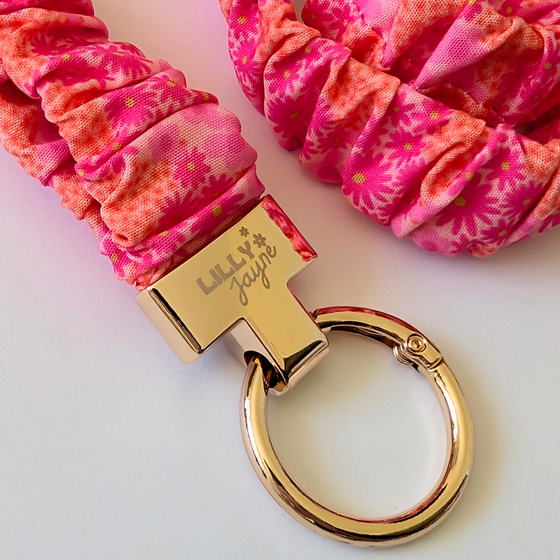 Pink scrunchie with gold keychain on a light pink background