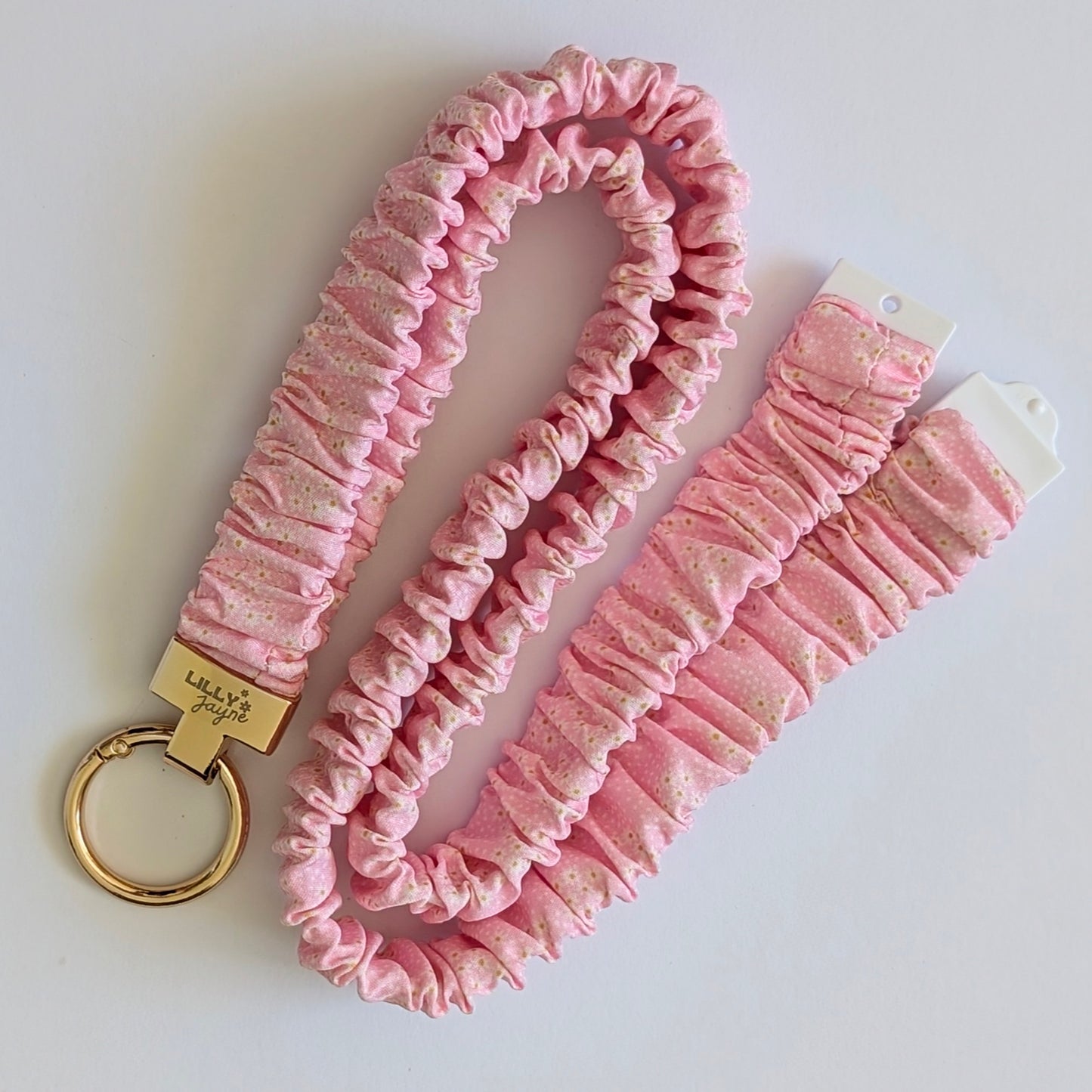 Pink textured keychain and strap with a gold ring on a white background