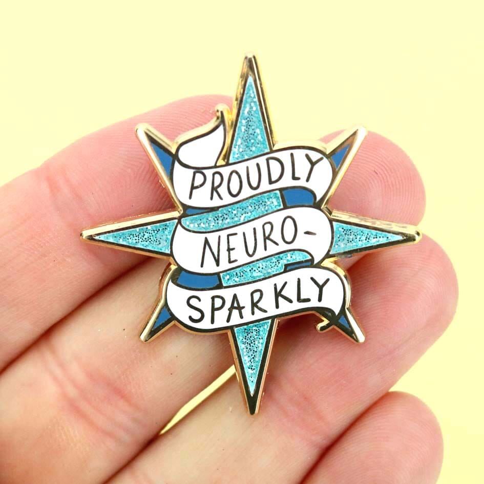 Star-shaped pin with 'Proudly Neuro-Sparkly' text held in a hand against a yellow background