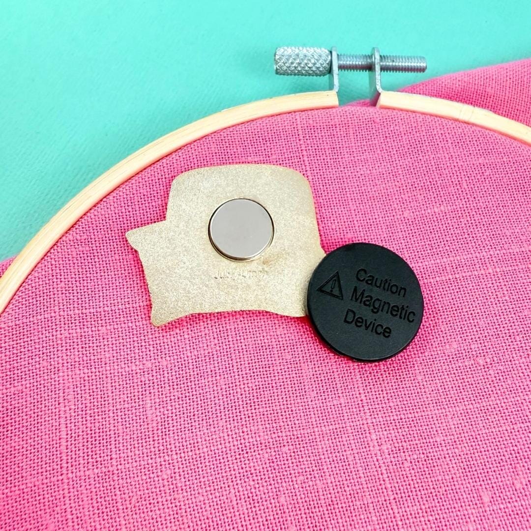 Magnetic device attached to a pink fabric background with a turquoise border