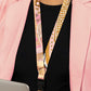 Person wearing a pink blazer with a patterned lanyard around their neck.