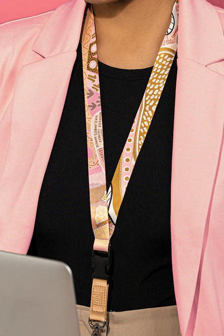 Person wearing a pink blazer with a patterned lanyard around their neck.