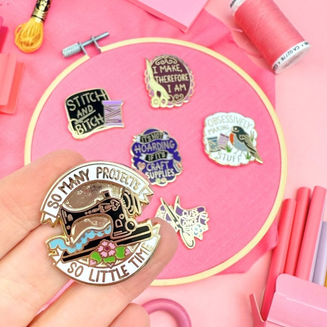 Collection of sewing-themed pins on a pink background with sewing supplies.