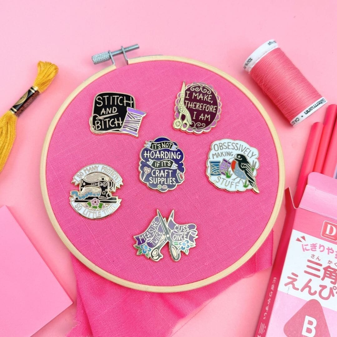 Embroidery hoop with colorful pins on a pink background