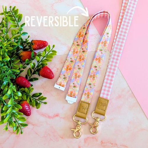 Reversible lanyard with floral and checkered patterns on a pink background with strawberries and leaves.