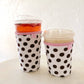 Two polka dot cups with pink lids on a white surface.