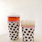 Two polka dot cups with pink lids on a white surface.