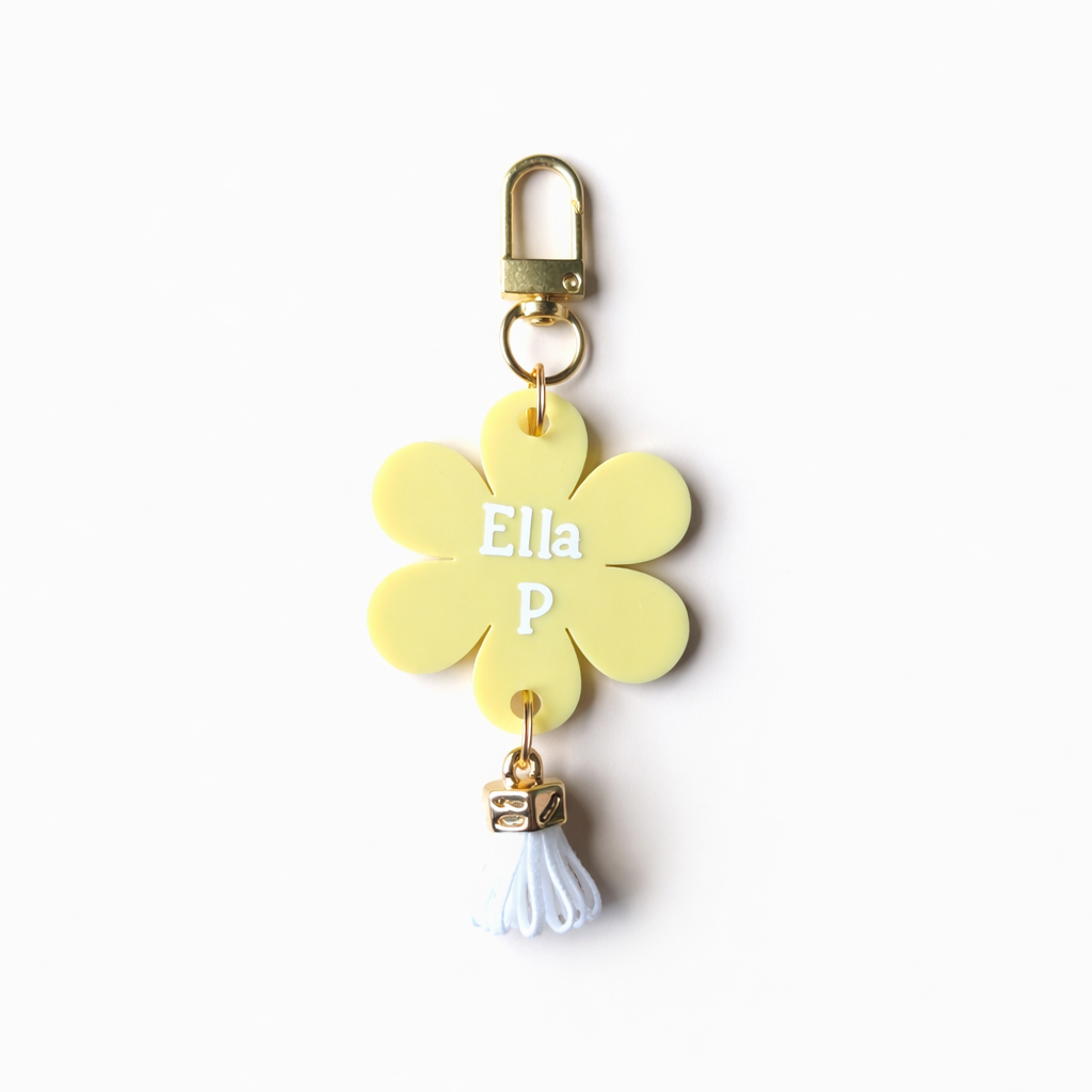 Yellow flower-shaped keychain with 'Ella P' on a white background