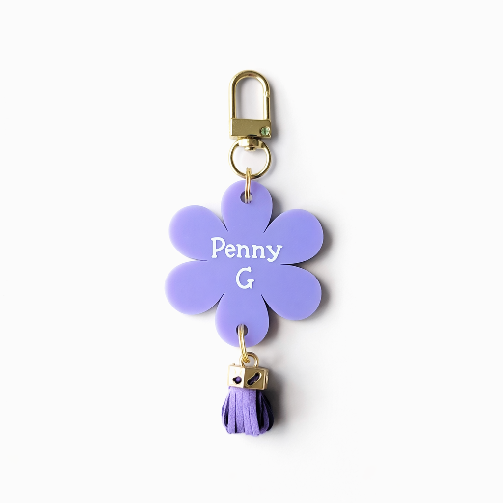 Purple flower-shaped keychain with 'Penny G' branding on a white background