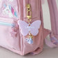 Pink backpack with a butterfly charm and unicorn patch on a light pink background