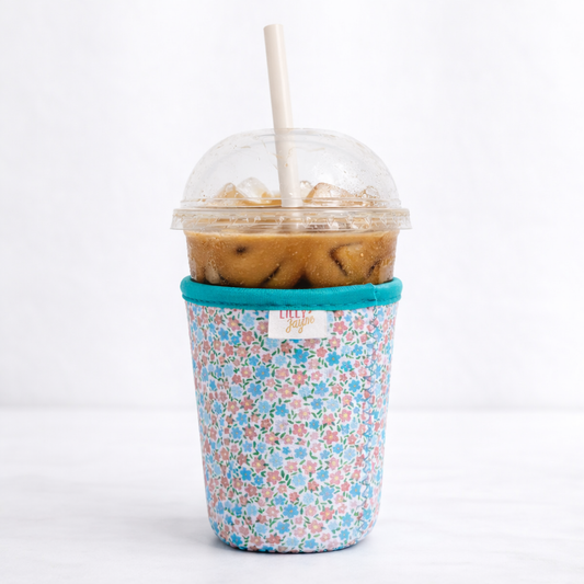 Floral-patterned cup sleeve with a plastic cup containing iced coffee on a white background