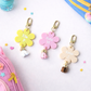 Three colorful flower-shaped keychains with names on a white background