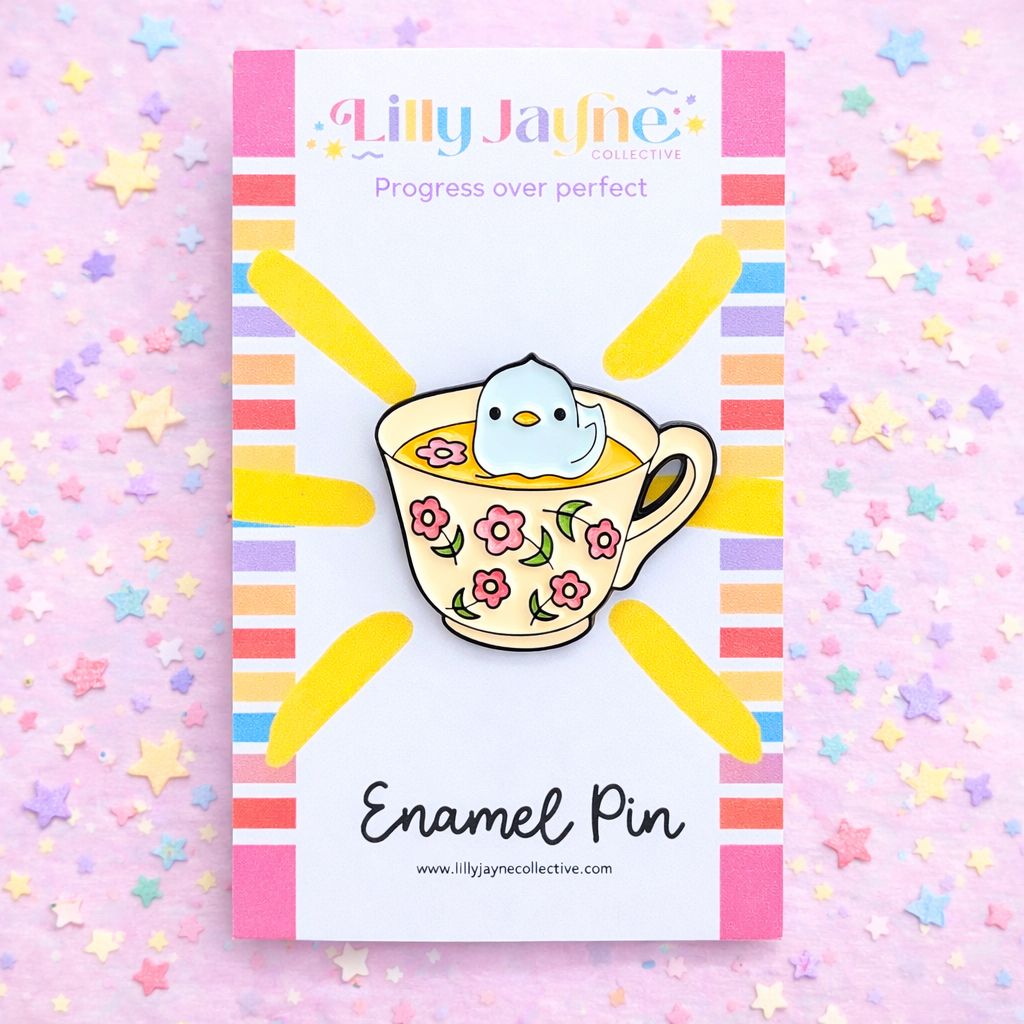 Enamel pin with a bird in a floral teacup on a colorful background