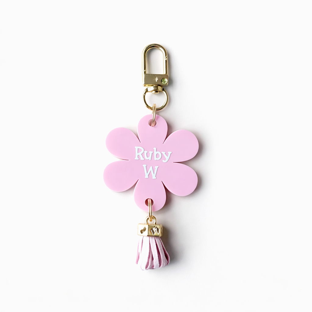 Pink flower-shaped keychain with 'Ruby W' engraving on a white background