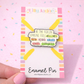 Enamel pin with motivational message on a colorful card, held against a pink background.