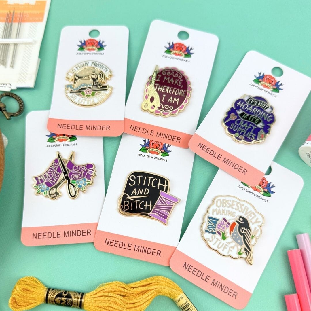 Collection of Needle Minder pins on their packaging with a green background