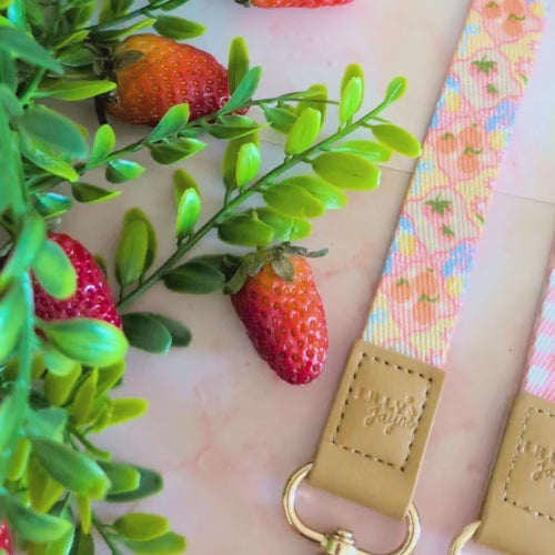 Reversible lanyard with floral and checkered patterns on a soft pink background with strawberries and leaves.