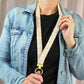 Person wearing a denim jacket holding a beige dog leash with a gold ring.