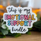 Colorful sticker with 'this is my emotional support kindle' text on a blurred background