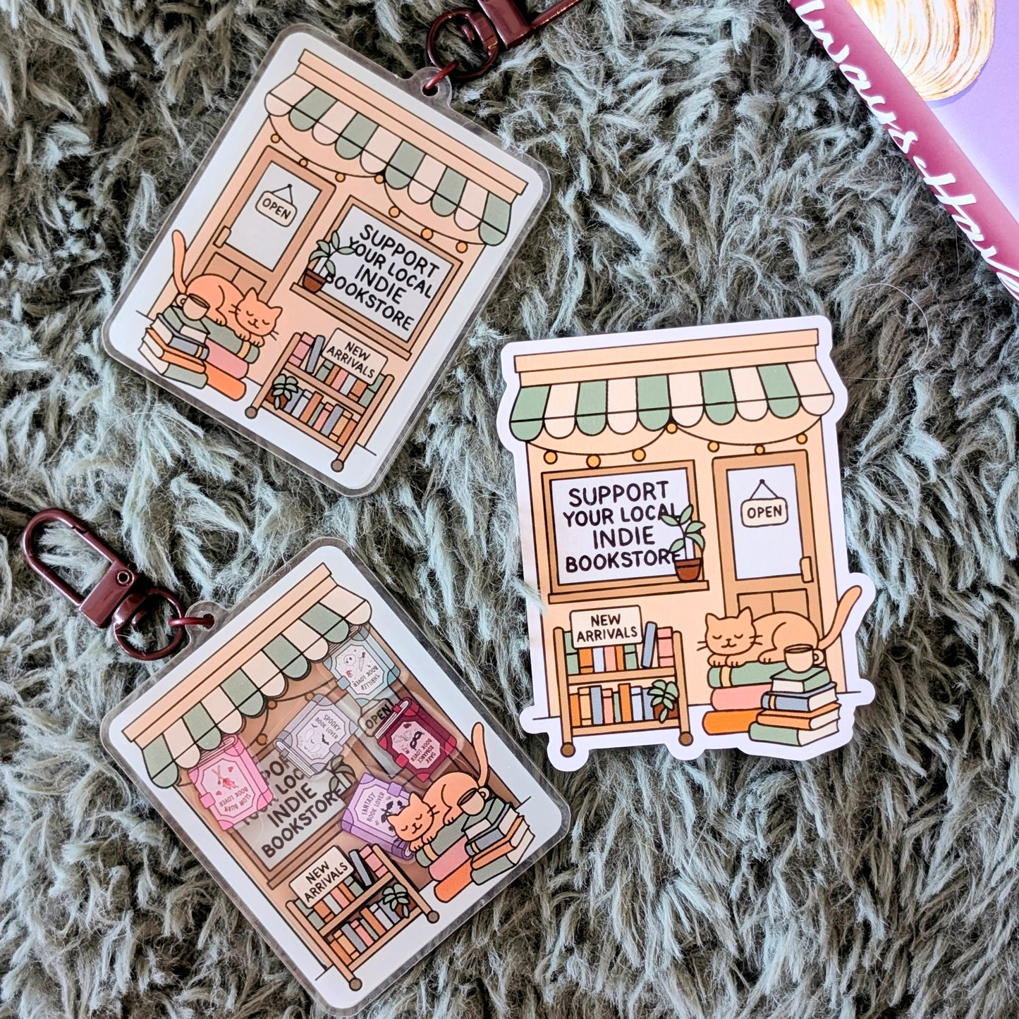 Three illustrated stickers of a bookstore with text 'Support Your Local Indie Bookstore' on a textured surface.