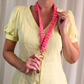 Person wearing a yellow dress holding a pink lanyard with a keychain against a plain background
